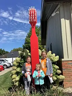 Three children by a big red toothbrush